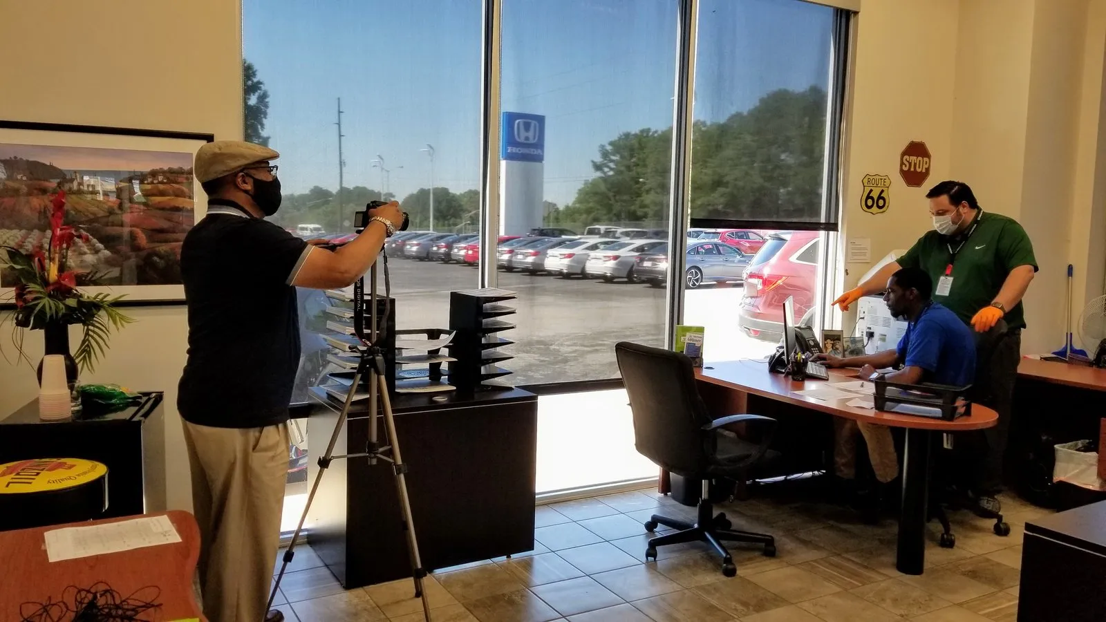 A videographer wearing a face mask films two people talking in a dental office